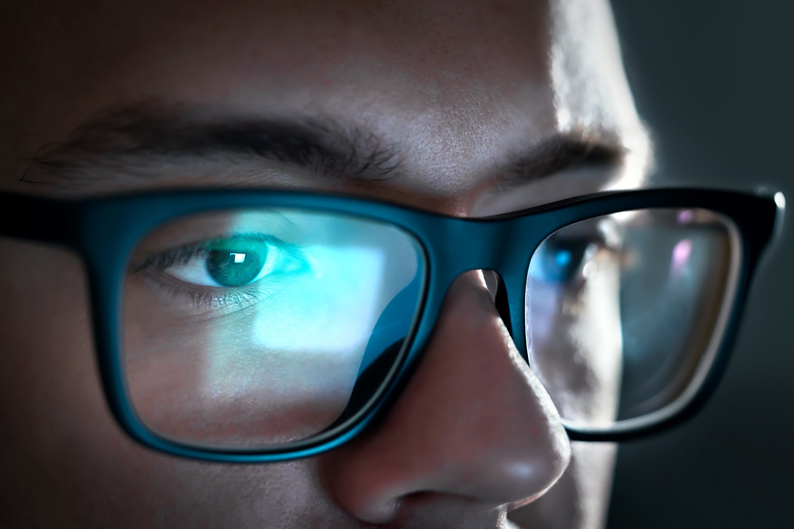 A person wearing glasses, with a computer screen reflected in the lenses.
