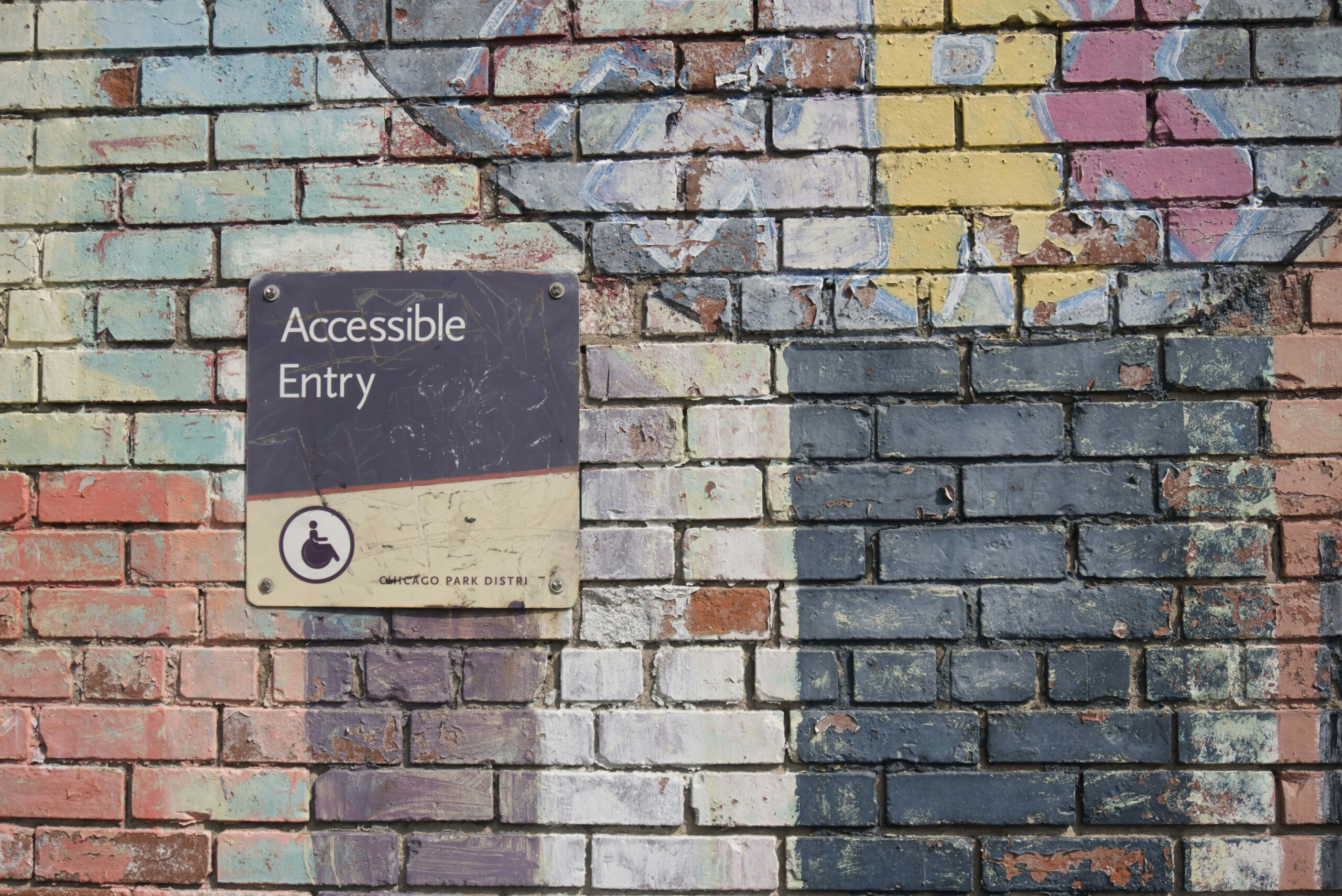 A brick wall with a sign that reads 'Accessible Entry'.