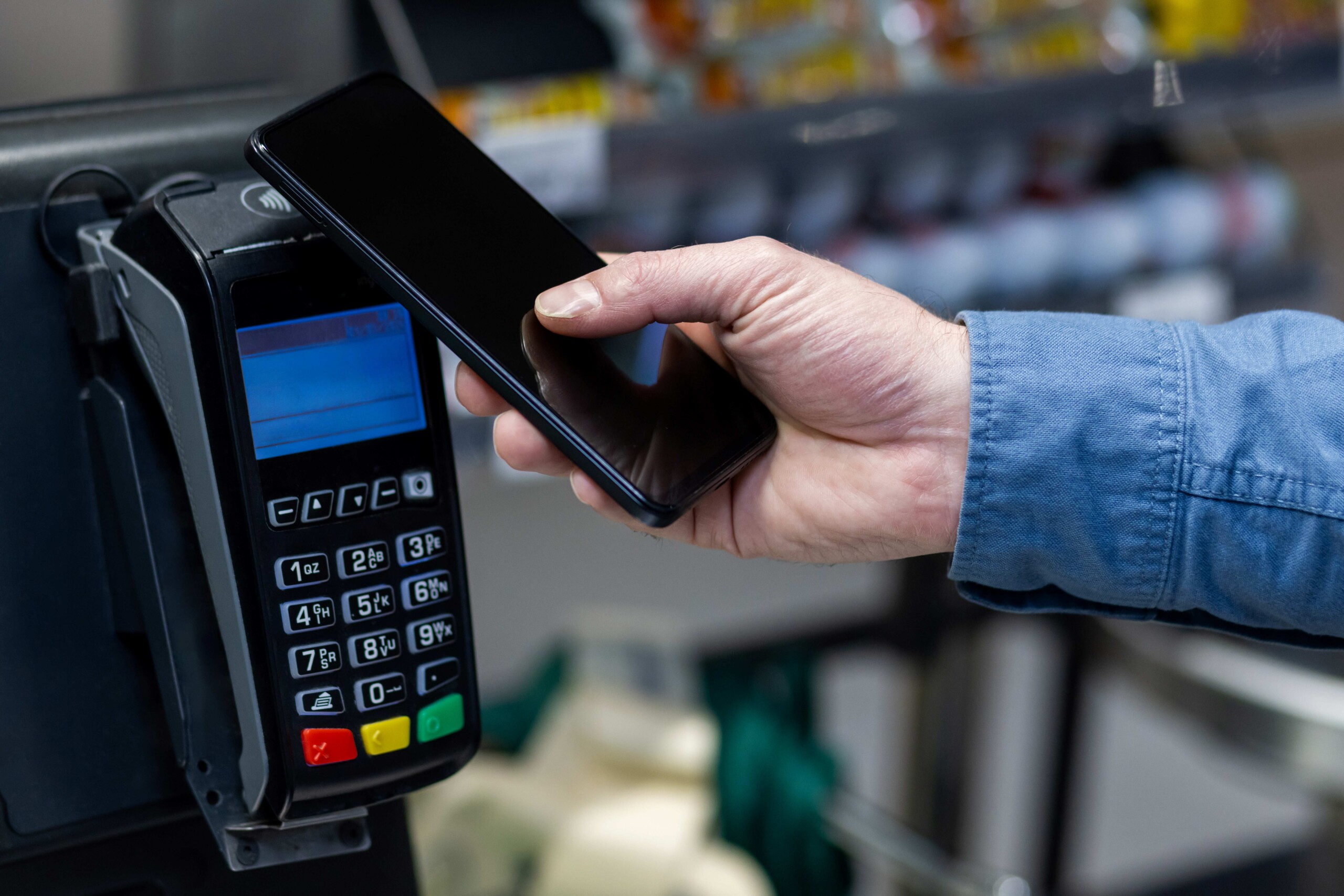 A person using their phone to pay at a self-checkout terminal